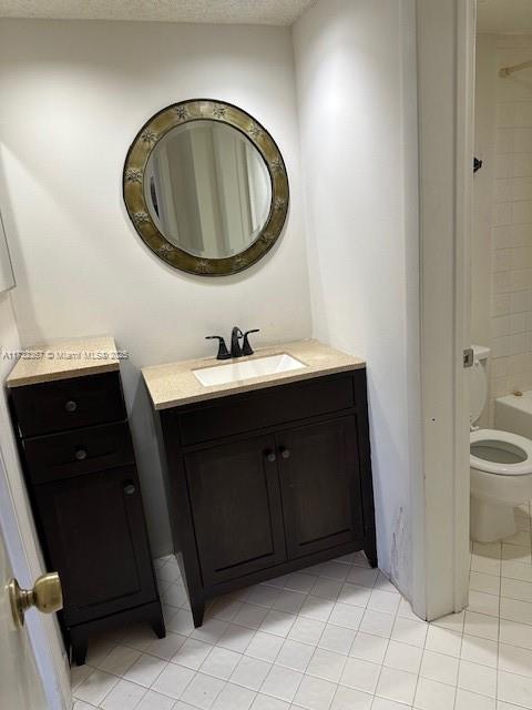 full bathroom featuring vanity, tiled shower / bath, tile patterned floors, and toilet