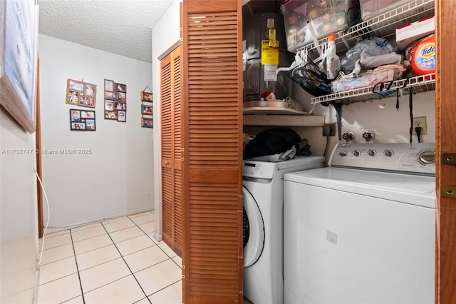 laundry room featuring washing machine and dryer, light tile patterned floors, and a textured ceiling