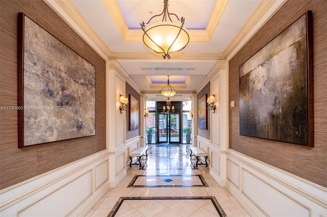 corridor with a raised ceiling and a chandelier