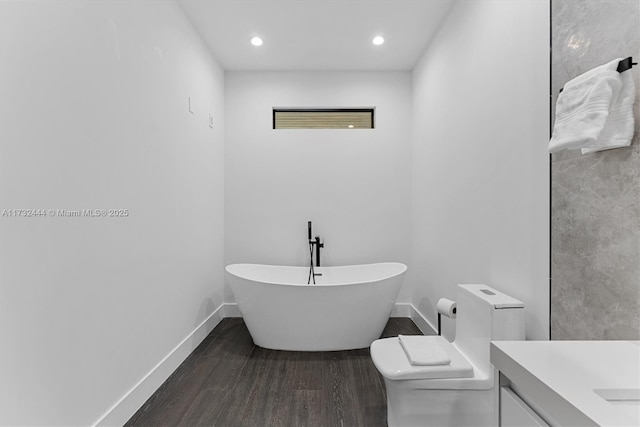 bathroom with a tub to relax in, toilet, hardwood / wood-style floors, and vanity