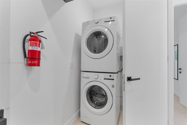 laundry area featuring stacked washer / dryer and light tile patterned floors