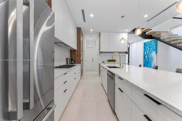 kitchen featuring pendant lighting, light tile patterned floors, sink, appliances with stainless steel finishes, and white cabinetry