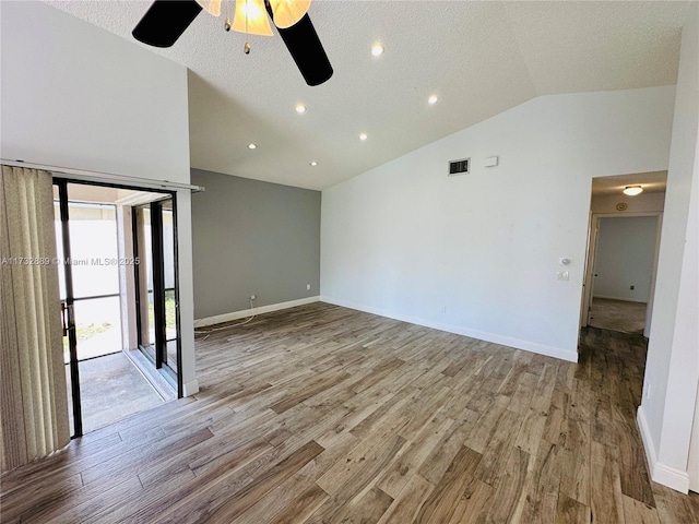 unfurnished room with lofted ceiling, a textured ceiling, and light wood-type flooring