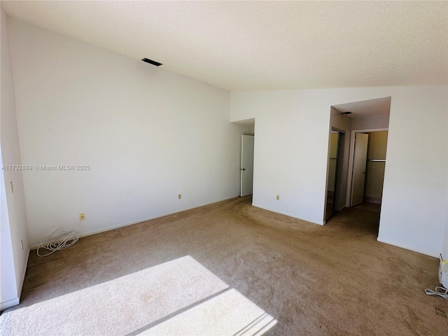 unfurnished bedroom featuring carpet floors, vaulted ceiling, and a textured ceiling