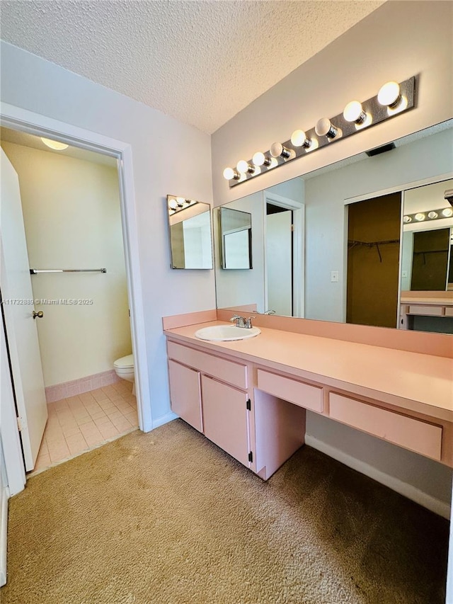 bathroom featuring vanity, toilet, tile patterned flooring, and a textured ceiling