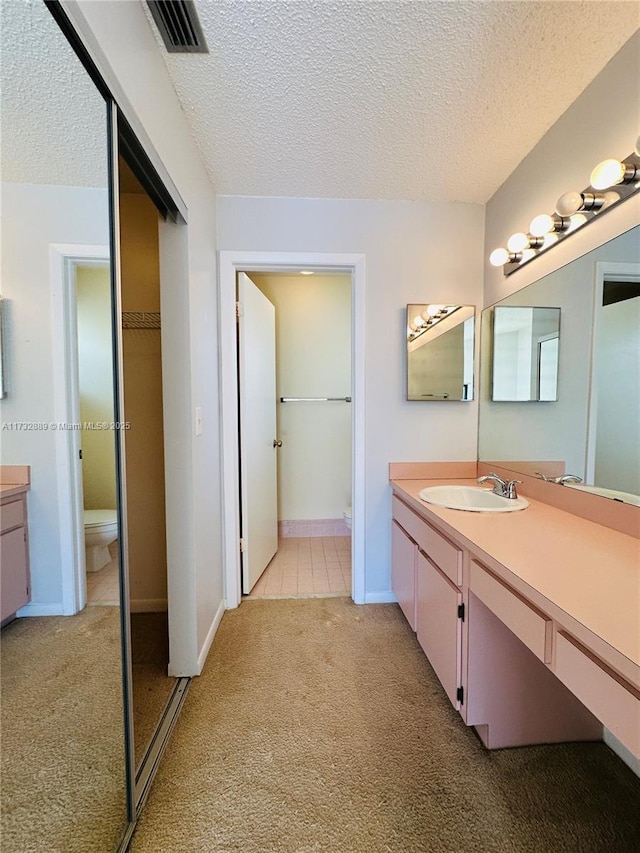 bathroom with vanity, toilet, and a textured ceiling