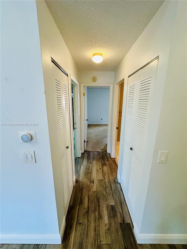 hallway featuring dark hardwood / wood-style floors and a textured ceiling