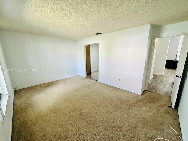 carpeted empty room with a textured ceiling