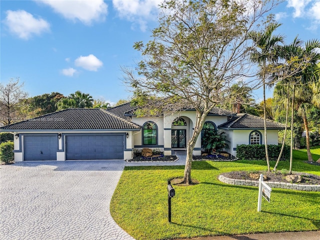 mediterranean / spanish home with an attached garage, a tile roof, and stucco siding