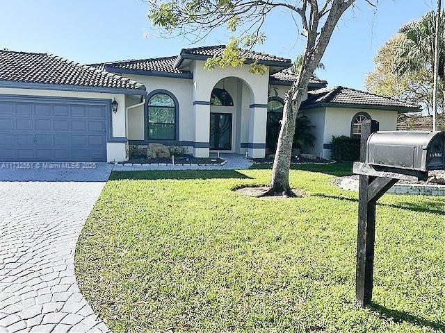 mediterranean / spanish home featuring a garage and a front lawn