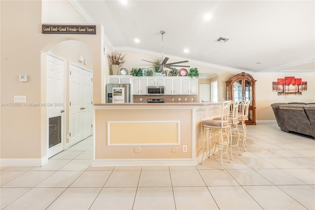 kitchen featuring lofted ceiling, light tile patterned floors, stainless steel appliances, visible vents, and crown molding