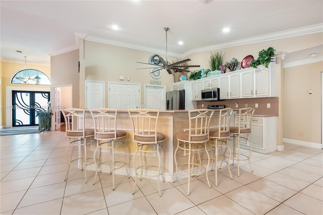 kitchen with light tile patterned floors, stainless steel appliances, a breakfast bar, and white cabinetry