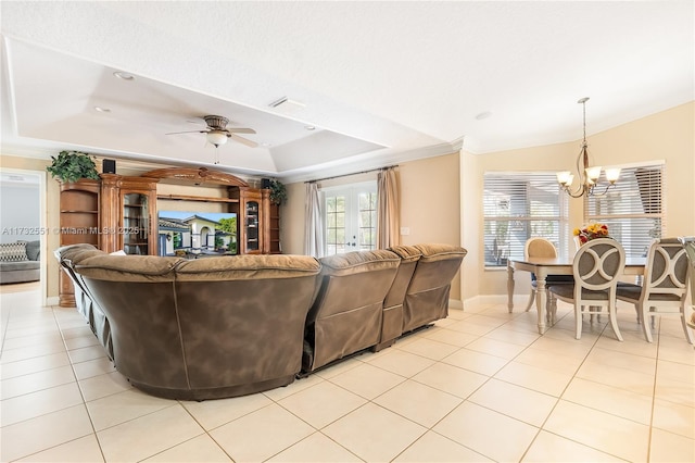 living area with light tile patterned floors, a tray ceiling, crown molding, french doors, and ceiling fan with notable chandelier