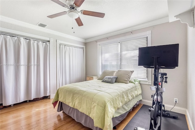 bedroom featuring wood finished floors, a ceiling fan, visible vents, baseboards, and ornamental molding