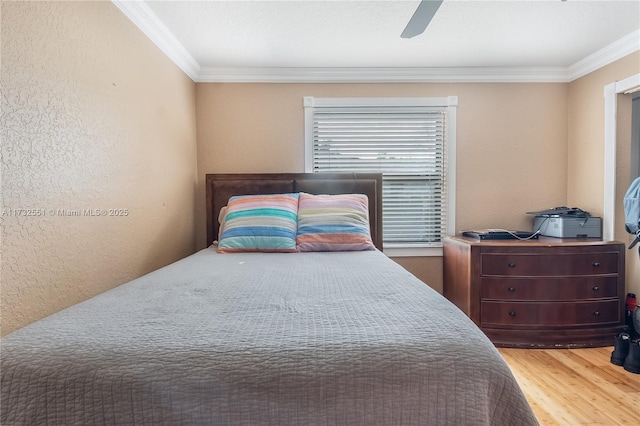 bedroom featuring crown molding, a ceiling fan, wood finished floors, and a textured wall