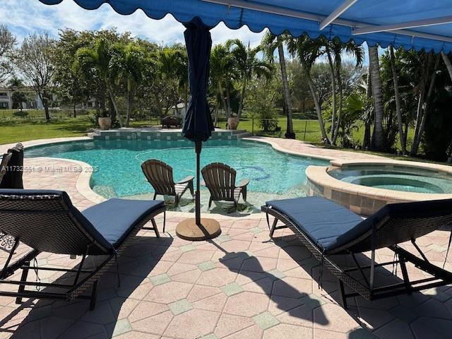 view of swimming pool featuring a pool with connected hot tub and a patio area