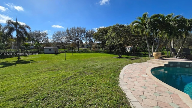 view of yard featuring a storage shed, a patio area, and an outbuilding