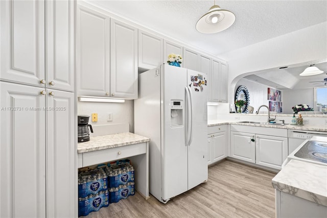 kitchen with sink, white cabinetry, a textured ceiling, light hardwood / wood-style flooring, and white refrigerator with ice dispenser