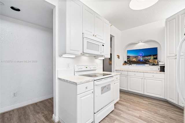 kitchen featuring white cabinetry, white appliances, light hardwood / wood-style flooring, and a textured ceiling