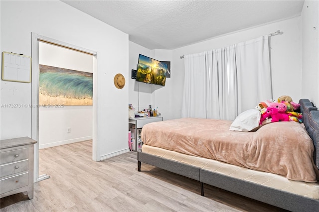 bedroom with light hardwood / wood-style floors and a textured ceiling