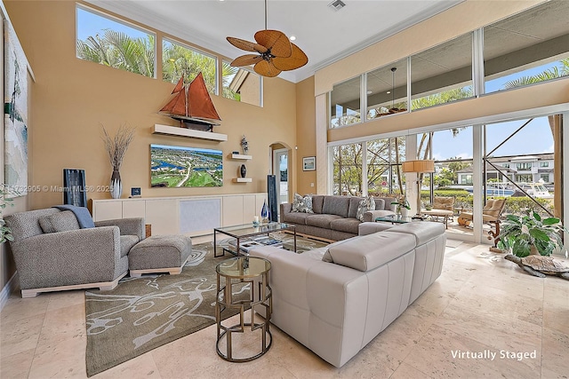 living room with crown molding, a towering ceiling, and ceiling fan