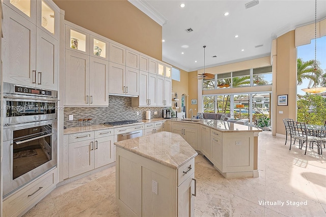 kitchen with pendant lighting, tasteful backsplash, light stone countertops, a kitchen island, and kitchen peninsula