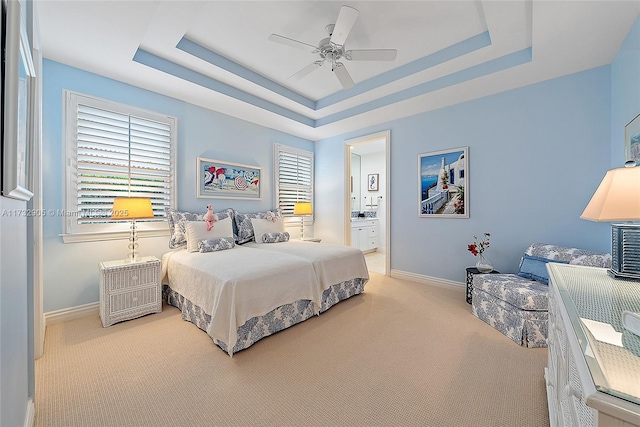 bedroom with multiple windows, a tray ceiling, light colored carpet, and ceiling fan