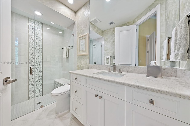 bathroom featuring vanity, toilet, a shower with shower door, and tile walls