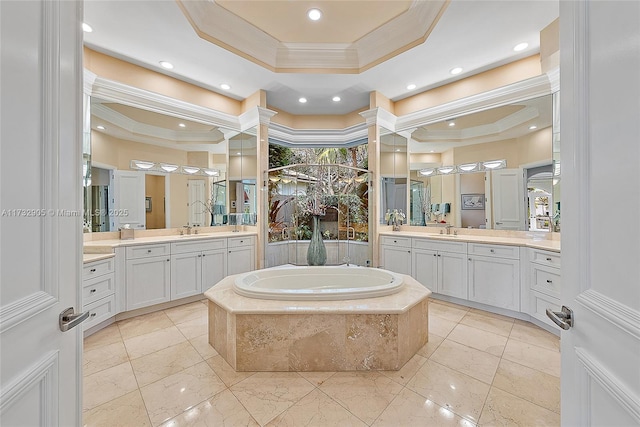 bathroom featuring a relaxing tiled tub, ornamental molding, vanity, and a raised ceiling