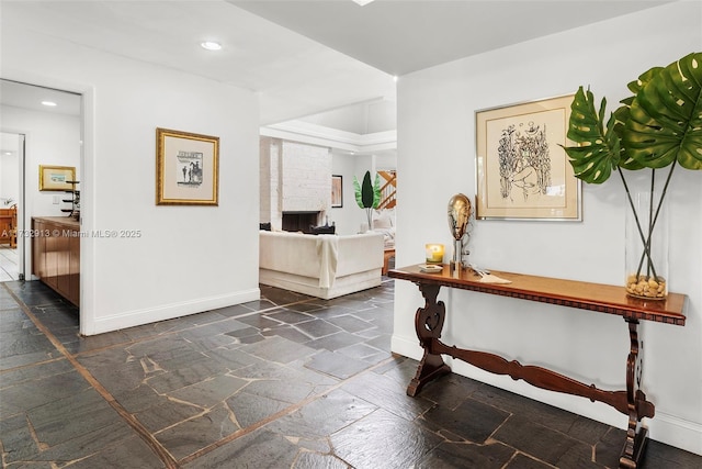 hall featuring baseboards, stone tile flooring, and recessed lighting