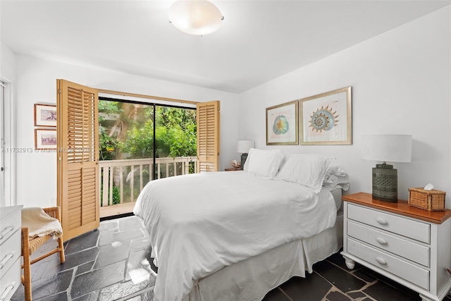 bedroom featuring stone tile floors and access to exterior