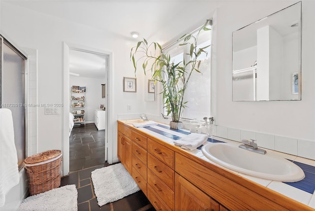 ensuite bathroom featuring a shower with shower door, a sink, and double vanity