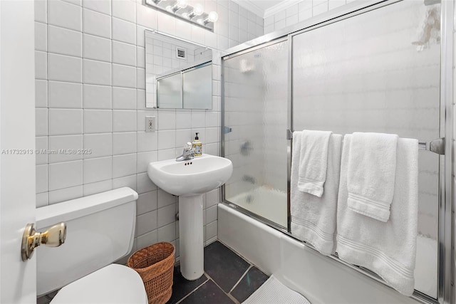 full bathroom with toilet, shower / bath combination with glass door, tile walls, and tile patterned floors