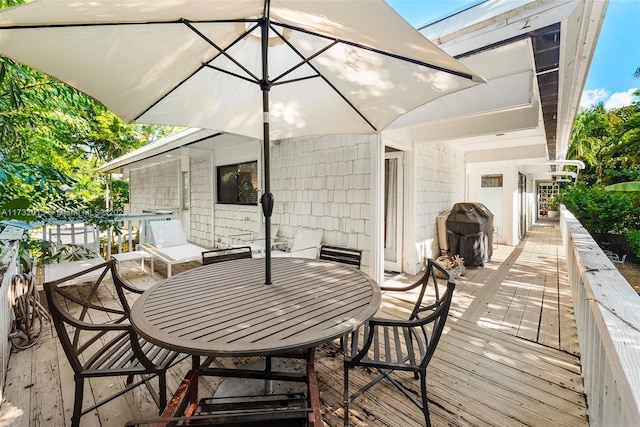 wooden deck with outdoor dining area and a grill