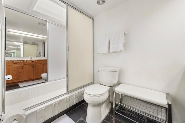 bathroom featuring toilet, a shower with door, and vanity