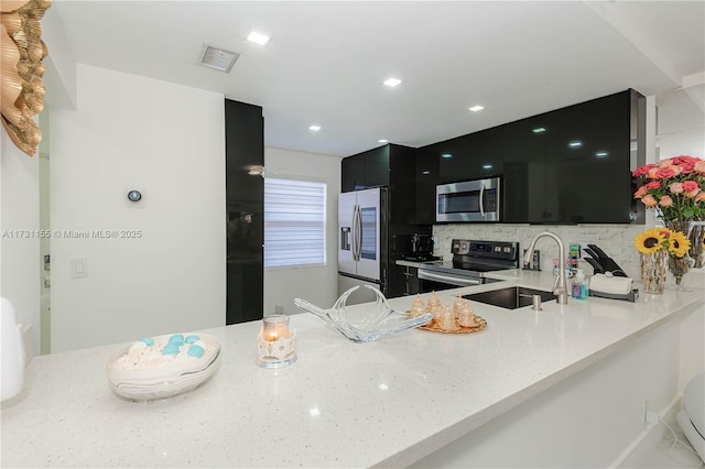 kitchen featuring appliances with stainless steel finishes, kitchen peninsula, sink, and decorative backsplash