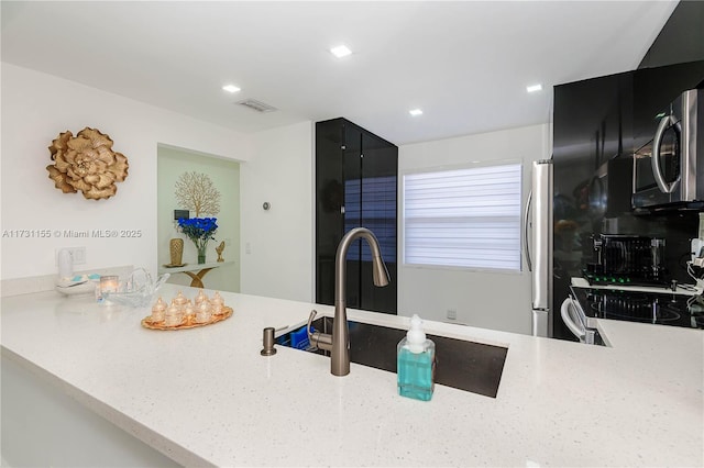 kitchen featuring light stone counters, sink, kitchen peninsula, and appliances with stainless steel finishes