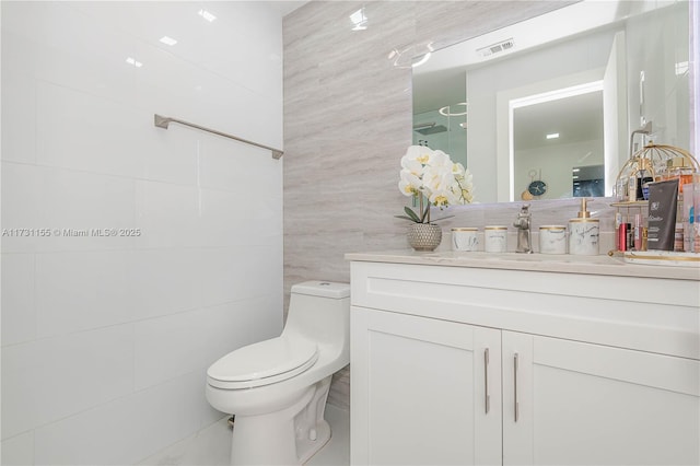 bathroom featuring vanity, tile walls, and toilet