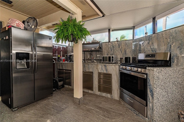 kitchen with stone countertops, sink, and appliances with stainless steel finishes