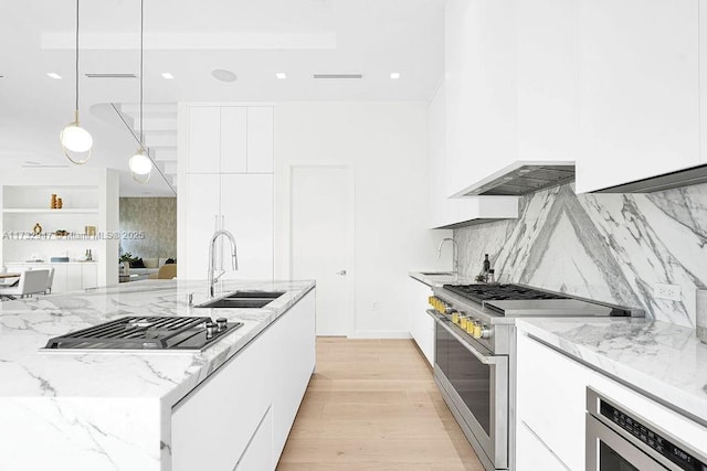 kitchen featuring appliances with stainless steel finishes, sink, white cabinets, and decorative light fixtures