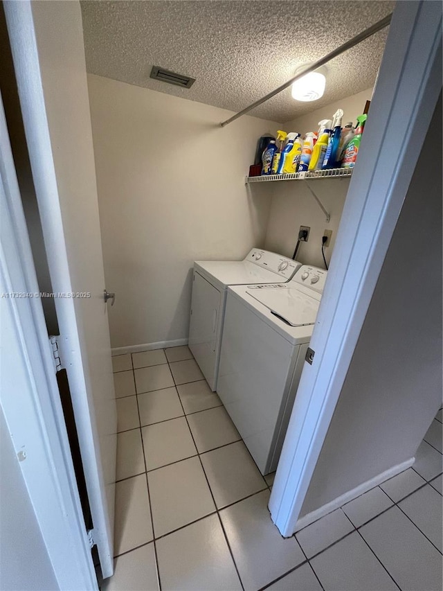 washroom with light tile patterned floors, a textured ceiling, and independent washer and dryer