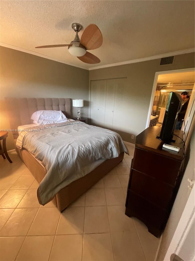 bedroom featuring ceiling fan, ornamental molding, a textured ceiling, and light tile patterned floors