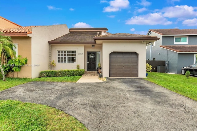 view of front of house with a garage, central AC, and a front yard