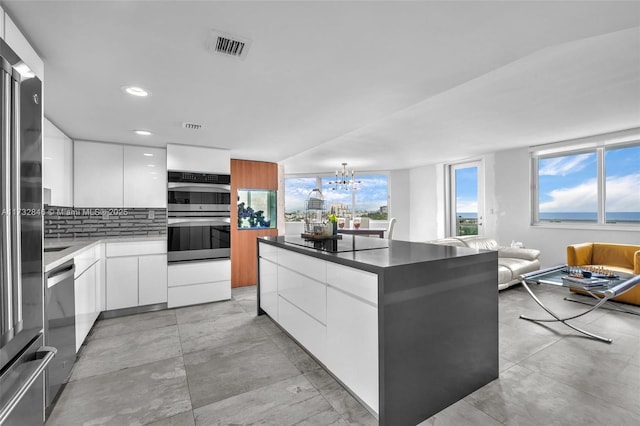 kitchen with white cabinetry, a center island, a chandelier, and black appliances