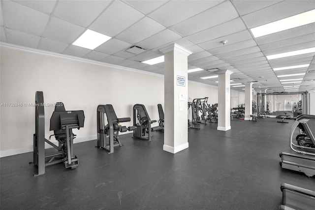 workout area featuring crown molding, a paneled ceiling, and ornate columns