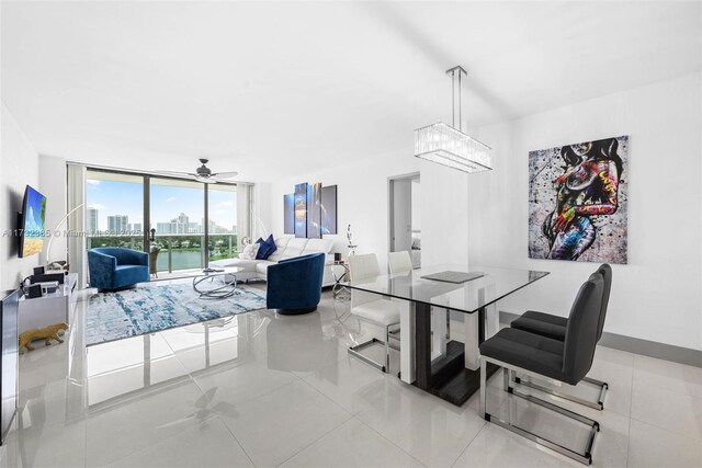 tiled dining room featuring ceiling fan, a water view, and a wall of windows