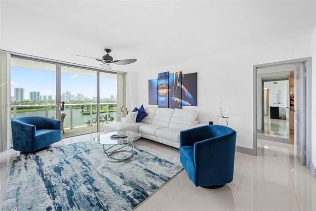 living room featuring light tile patterned floors, ceiling fan, floor to ceiling windows, a water view, and french doors