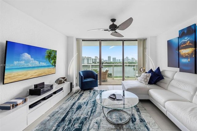 living room featuring a wall of windows, ceiling fan, and a water view