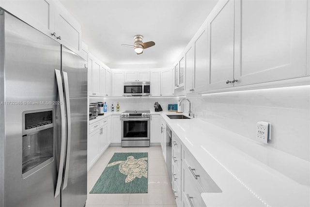 kitchen featuring light tile patterned floors, a sink, light countertops, white cabinetry, and stainless steel appliances