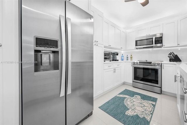 kitchen featuring light tile patterned floors, stainless steel appliances, white cabinets, and ceiling fan